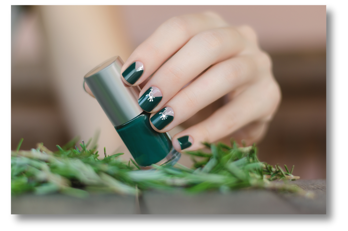 Female hand with green nail design holding nail polish bottle