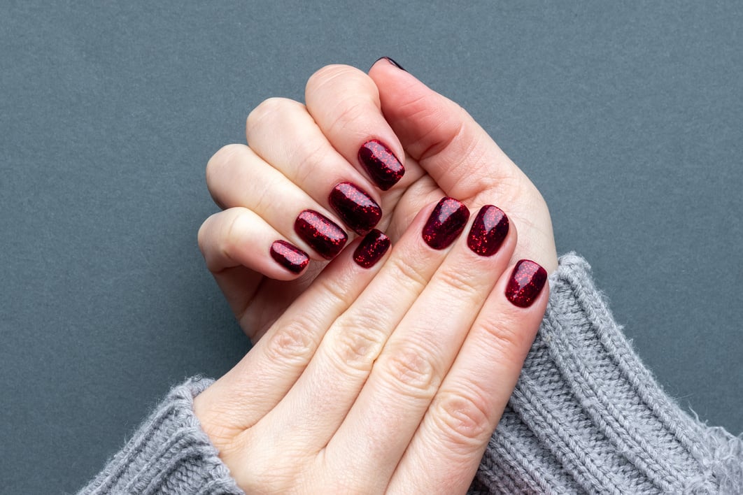 Female Hands with Beautiful Manicure - Dark Red Glittered Nails